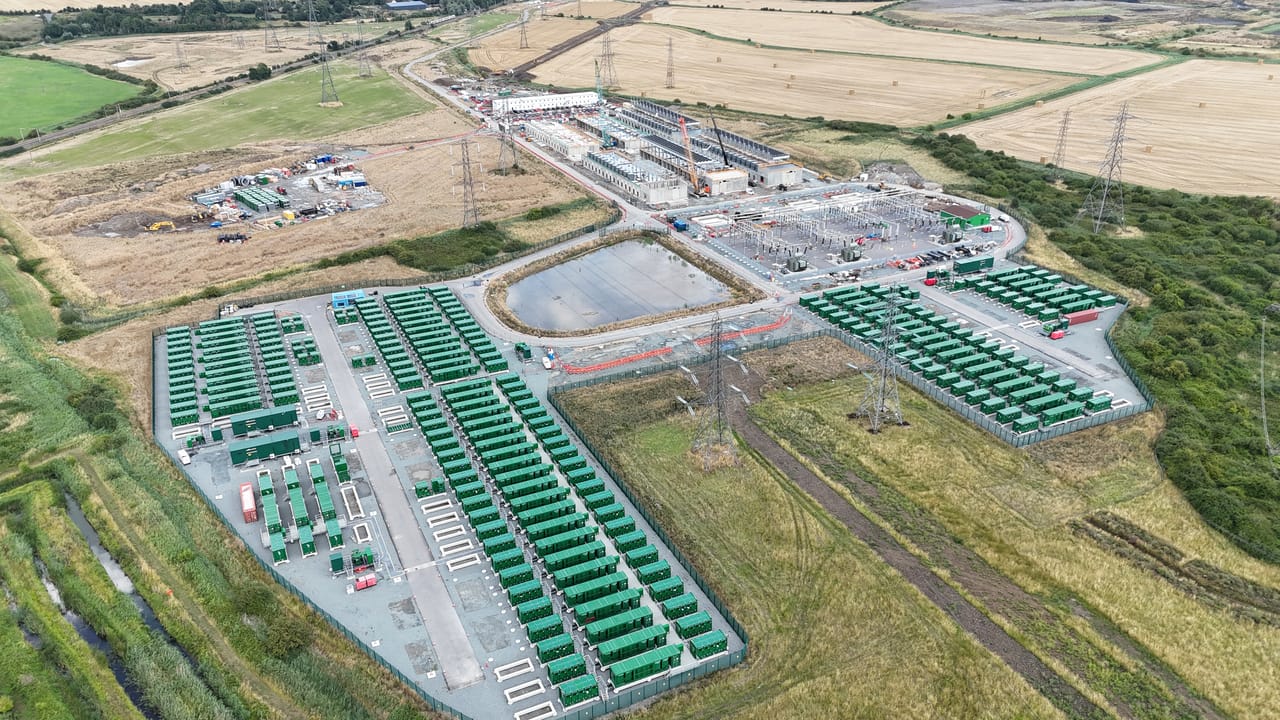 Groot batterijpark van Statera in Thurrock, Essex, met rijen batterijcontainers naast een veldstation en hoogspanningsmasten.
